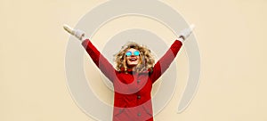 Winter season is open! Happy laughing woman raising her hands up and looking up enjoys wearing red jacket with fur hood,