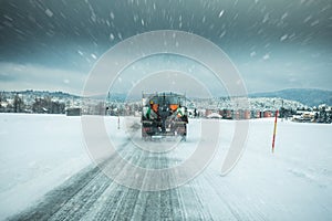 Winter service truck or gritter spreading salt on the road surface to prevent icing in stormy snow winter day.