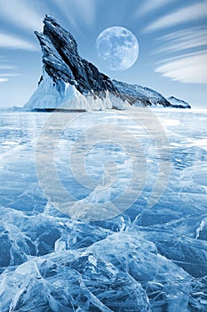 Winter Siberian landscape. Lake Bakal. Transparent patterned ice surface and mighty rock. Frosty blue image.