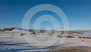 Winter Siberian landscape. On the shore of the frozen lake there are wooden houses