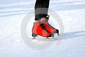 Winter skating rink. Red skates skate on the ice. Active family sport during the winter holidays and cold season