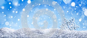 Winter snow background with decorative snowflake against blue sky. Banner format. Beautiful wintertime holiday scene