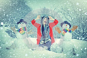 Winter snow blue toned. Happy girl winter portrait. Happy snowman standing in Christmas landscape. Winter woman in