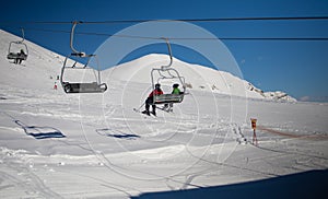 Ski lift empty ropeway on hilghland alpine mountain winter resort on bright sunny evening . Ski chairlift cable way with people