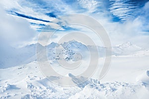 Winter snow-covered mountains and blue sky with white clouds