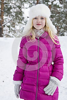 In winter, snow-covered pine forest plays a beautiful little girl.