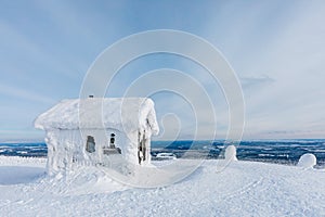 Winter snow covered wood hut. Frozen log cabin in Finland