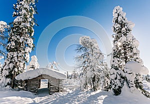 Winter snow covered wood hut. Frozen log cabin in Finland