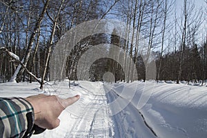 Winter. snow. road. the finger of the hand shows the direction of movement.