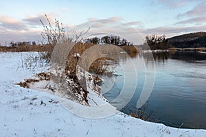 Winter snowy evening view on mirror river shore