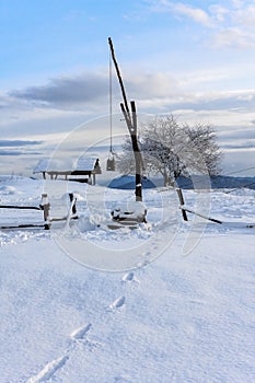 Winter snowy rustic scenic landscape with a draw well and footprints