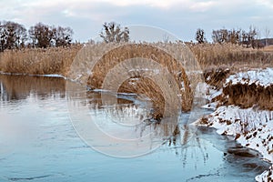 Winter snowy sunset view on frozen river shore