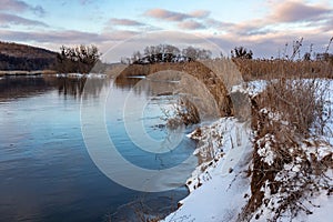 Winter snowy sunset view on river shore, Ukraine