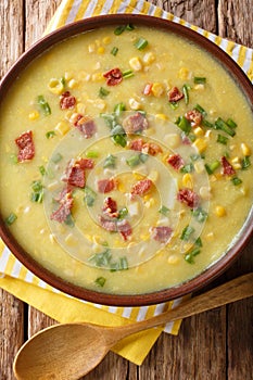 Winter soup corn chowder with bacon and green onions close-up in a plate. Vertical top view