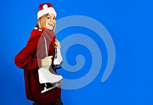 Winter sport activity. Smiling woman in warm sweater, red scarf and Santa hat with ice skates. Pretty girl in warm