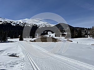 A winter sport cross-country ski trail around a frozen alpine Heidsee lake (Igl Lai lake) in the Swiss winter resorts