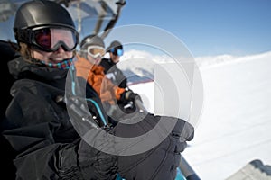 Winter sport friends in chair lift with ticket