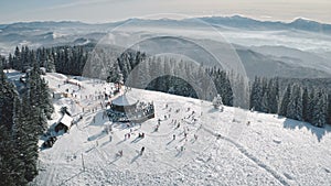 Winter sport resort at snow mountain top aerial. People at nature landscape. Ski slope at fir forest