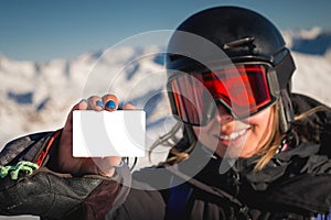 Winter sports girl holding a ski pass and smiling. A concept illustrating the entry fee for skiing. Happy woman showing