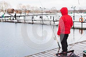 Winter, spring fishing on paid snow covered ice pond, lake in country club. Catching fish with spinner,bait, net.Fisherman with