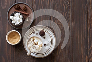 Winter still life- cup of coffee, marshmallows and fir cones on dark wooden background