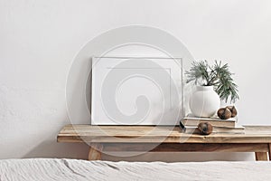 Winter still life. Horizontal white frame mockup on vintage wooden bench, table. Modern white ceramic vase with pine