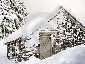 Stone cabin buried under ice and snow in winter