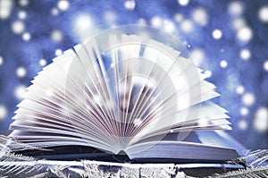 Winter story. Open book on wooden snowy blue background