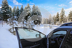 WInter street with lots of snow with private driveway and car with open door and gates