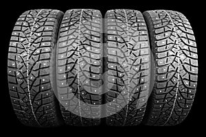 Winter studded tire. Winter car tires isolated on black background. Tire stack background. Tyre protector close up. Square