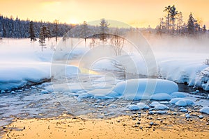 Winter sundown in forest and river with beautiful misty fog