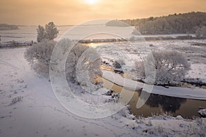 Winter sunrise. Beautiful winter scene on river in frosty morning. Aerial view of winter nature. Snowy landscape from above