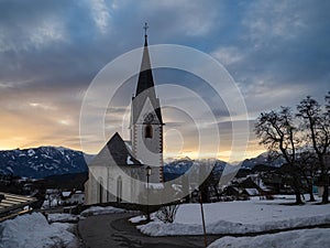 Winter sunset landscape of an old austrian church in an alps village, snowy mountains, Wallfahrtskirche Maria Schnee Matzelsdorf