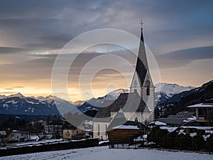Winter sunset landscape of an old austrian church in an alps village, snowy mountains, Wallfahrtskirche Maria Schnee Matzelsdorf