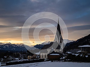 Winter sunset landscape of an old austrian church in an alps village, snowy mountains, Wallfahrtskirche Maria Schnee Matzelsdorf