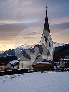 Winter sunset landscape of an old austrian church in an alps village, snowy mountains, Wallfahrtskirche Maria Schnee Matzelsdorf