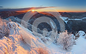 Zimný západ slnka v horách s mrakmi
