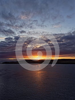 A Winter Sunset over the isle of Bressay and Bressay Sound, with the orange evening light being reflected in the calm water.