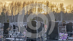 Winter sunset over a snow covered cemetery with dark headstones and trees. Afterlife. Samsara concepts.