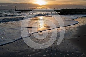 Winter sunset reflecting in the waves on the sandy Western Undercliff Beach in Ramsgate, Kent