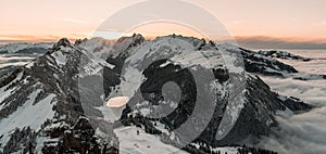 winter sunset on top of the swiss mountain hoher kasten in appenzell switzerland with clouds and beautiful mountain lake