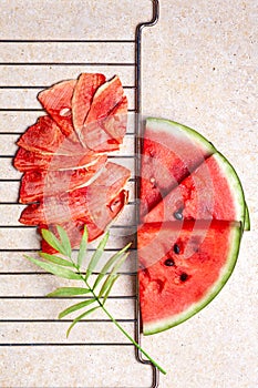 Winter supplies: slices of dried watermelon with fresh pieces on light background with grid