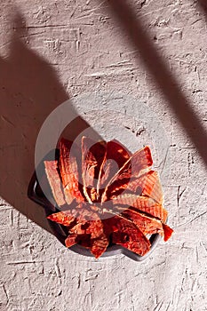 Winter supplies: slices of dried watermelon in wooden plate on white background with deep shadow