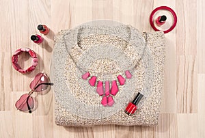 Winter sweater and pink accessories arranged on the floor.