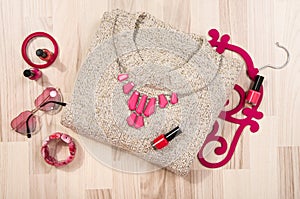 Winter sweater and pink accessories arranged on the floor.