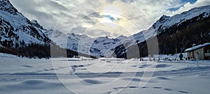 Winter in the swiss alps, Switzerland. Panoramic view. Snowy winter landscape in the mountains with fir trees and wooden fence.