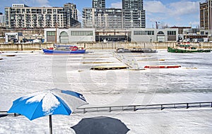 Winter time in  the marina of Montreal Old Port with Beach umbrella  boats before condos