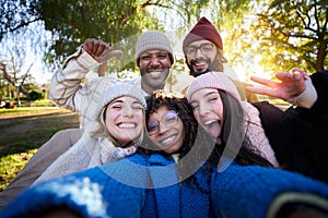 Winter time smiling selfie of a happy group of multicultural friends looking at the camera.