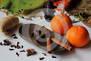 Winter time - two tangerines and spice - ginger, cloves, star aniseed, black pepper and cinnamon arranged on a wooden bowl