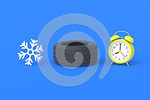 Winter tire near alarm clock and snowflake. Time, speed of car wheel replacement